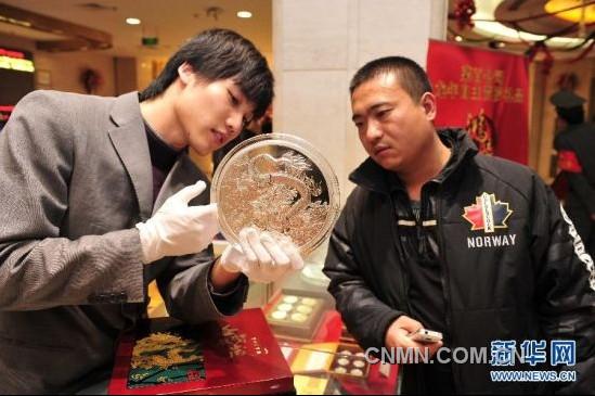 12月21日，工作人員向顧客介紹一款5公斤重的壬辰賀歲紀(jì)念大銀章，其正面的“金龍降喜”圖案，寓意對龍年萬事亨通的美好祝福。