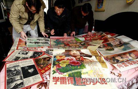 3月1日，房冠龍（中）在家中整理關(guān)于雷鋒的宣傳海報(bào)。