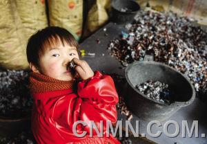 個小朋友在臺州市路橋區(qū)峰江街道一家拆解小作坊內(nèi)玩分揀出來的金屬。